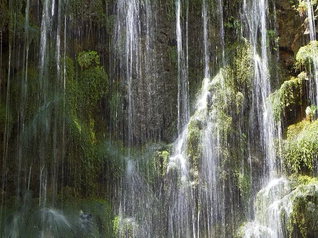 Nahaufnahme eines herabstürzenden Wasserfalls über moosbedeckte Felsen