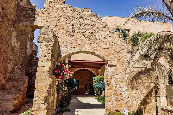 Arche en pierre menant à la cour d’un vieux bâtiment avec des bougainvilliers