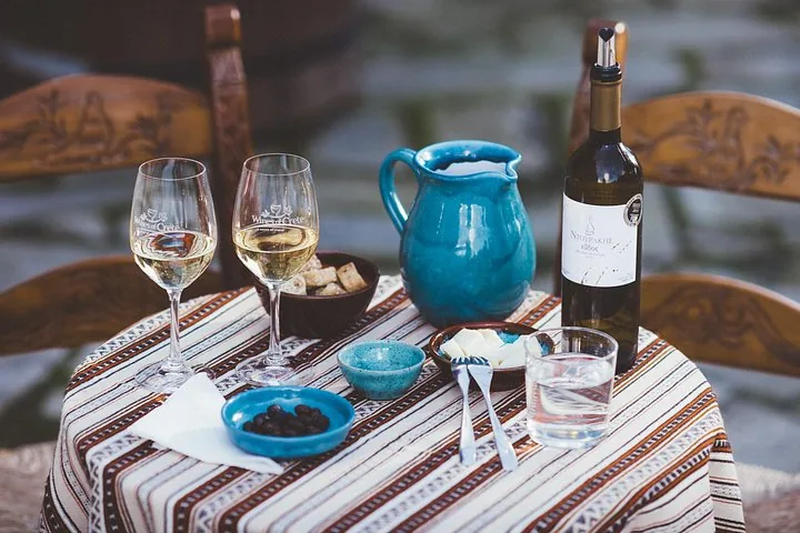 A bottle of wine, two glasses, and appetizers on a table