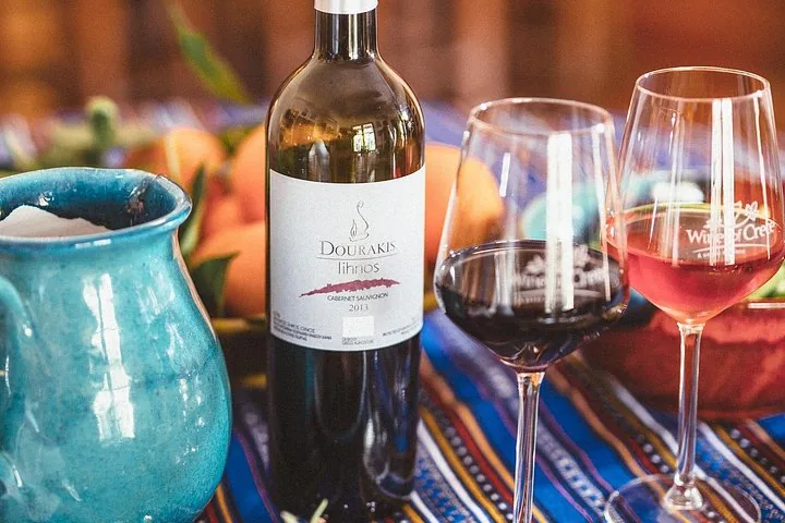 Close-up of a bottle of Dourakis wine and two filled wine glasses